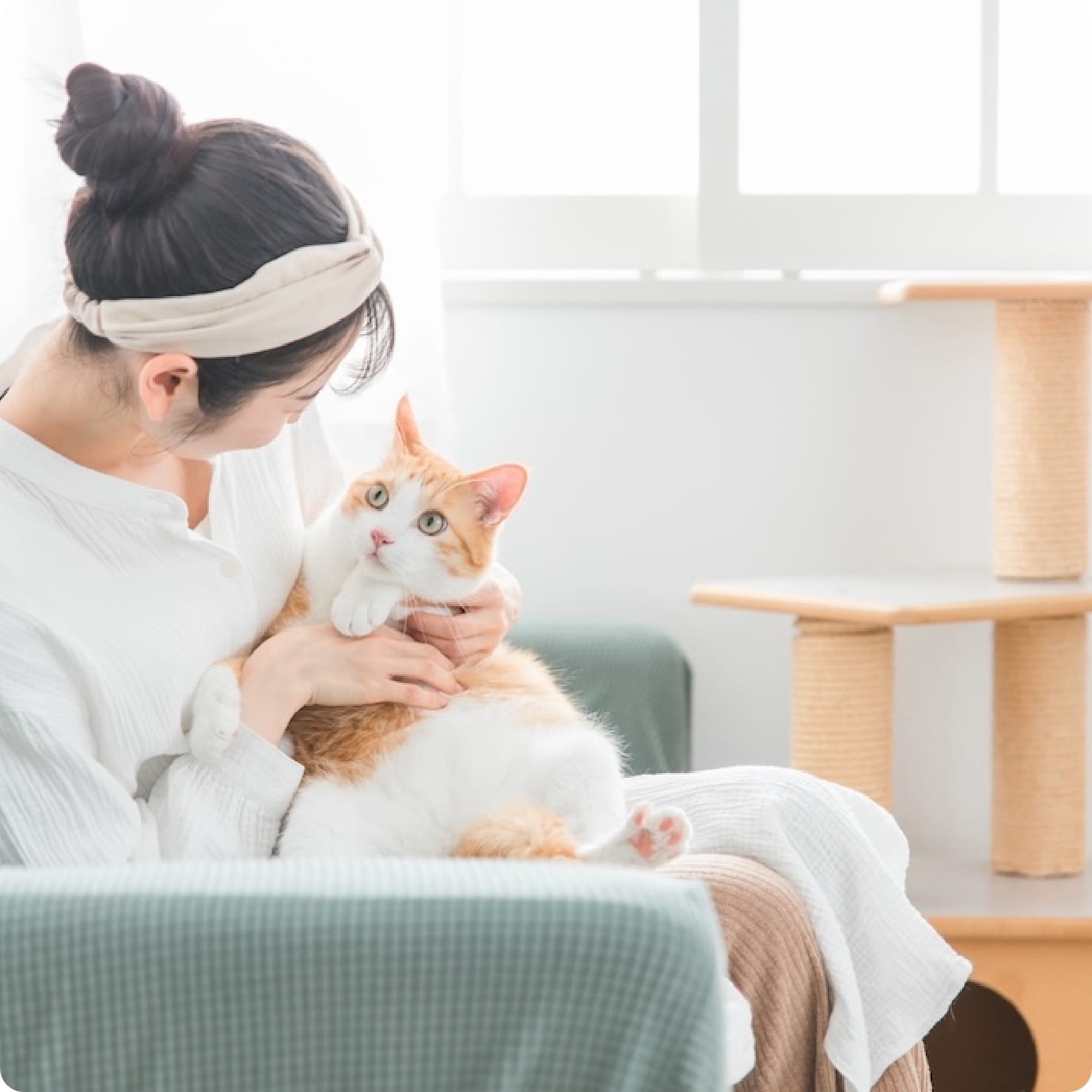 猫が少し驚いたような表情で女性の腕の中にいるシーン
