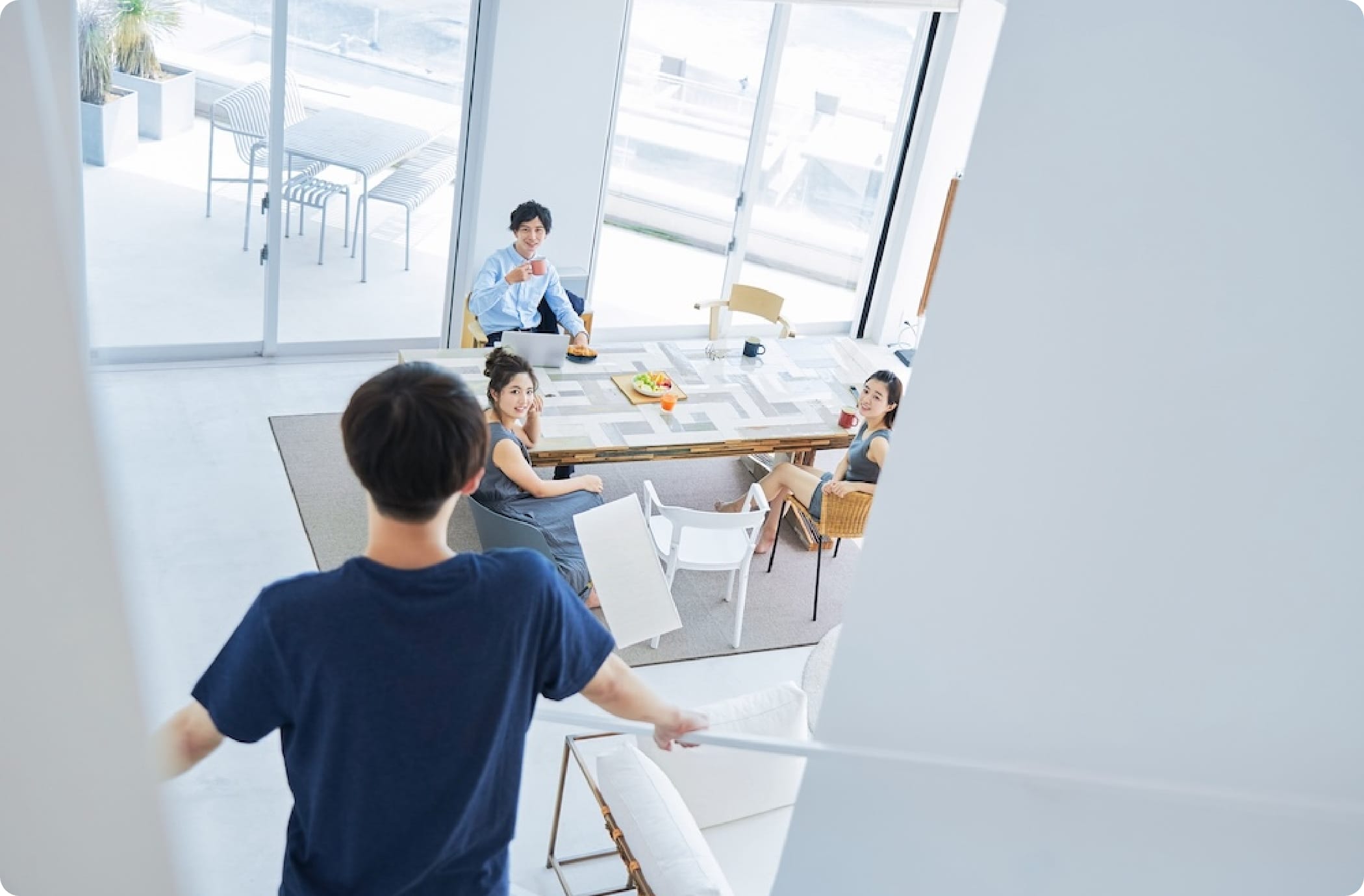 明るいリビングで4人の若者がテーブルを囲み談笑している様子